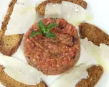 Delicioso tartar de tomate fresco, servido con finas láminas de queso y tostadas crujientes.