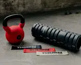 Czerwony kettlebell, wałek do masażu i taśmy oporowe. Idealny zestaw, by zacząć treningi z kettlebell.