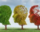 Tre alberi a forma di testa umana, dal verde rigoglioso al rosso spoglio, simboleggiano il declino cognitivo.
