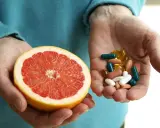 Dłonie trzymają połówkę grejpfruta i garść tabletek. Czy grejpfrut kcal to zdrowa alternatywa dla suplementów?