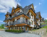 Nowoczesne apartamenty Bachledzki Wierch z drewnianymi elementami i balkonami, otoczone zielenią.