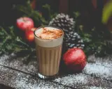 En krämig kaffedrink med kanel, omgiven av juliga äpplen och granris. Perfekt för mysiga stunder och inspirerar till egna kaffedrinkar recept.