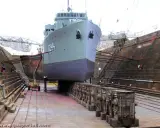 Un grand navire est en cale sèche, soutenu par des structures en bois. Le support bateau cale sèche est essentiel pour les réparations.