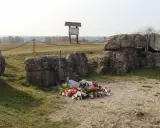 Pomnik na Górze Strękowej z krzyżem i wieńcami. W tle widoczne bunkry i krajobraz.