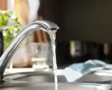 Wasserhahn mit integriertem Durchlauferhitzer, Testsieger. Wasser fließt aus dem Hahn in die Spüle.