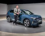 Ein Mann lehnt lässig an einem blauen Audi Q4 e-tron 2026.