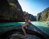 Kobieta w bikini na łodzi, podróżująca po turkusowej wodzie między klifami. Idealne miejsce na wakacje na własną rękę.