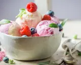 Deliciosos helados caseros de fresa y vainilla, adornados con frambuesas y arándanos frescos.