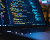 Laptop z kolorowym kodem, gdzie niektóre linie są przekreślone równa się, sugerując błędy lub zmiany w programie.