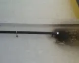 Tuyau d'évacuation noir d'un poêle à pellet ventouse, fixé au mur blanc, avec des traces de suie autour de la sortie.