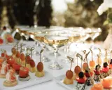 Elegantes aperitivos para bodas: camarones, salmón, queso y frutas en brochetas, junto a copas de champán.