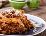 Pappardelle z bogatym sosem bolognese, idealne pytanie: jakie mięso do spaghetti? Posypane parmezanem.
