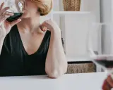 Kobieta z krótkimi blond włosami pije czerwone wino. Czy zastanawiasz się, jak hashimoto a alkohol wpływają na zdrowie?