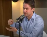 Michael van de Poppe w niebieskiej koszuli mówi do mikrofonu, gestykulując.