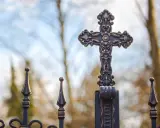 Krzyż na metalowym ogrodzeniu, symbol nadziei i walki z siedmioma grzechami głównymi.
