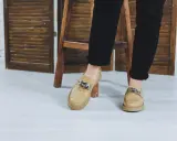 Beżowe, lakierowane buty bez skarpet z ozdobnym łańcuchem, idealne do czarnych spodni.