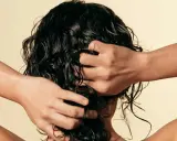 Manos peinando cabello oscuro y rizado, con un toque de cabello esponjado.