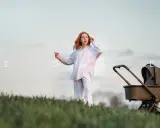 Kobieta z rudymi włosami i wózek dziecięcy Venicci Edge na tle nieba.