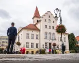 Mężczyzna podziwia ratusz, jedną z głównych trzebnickich atrakcji. W tle czerwone serce i kwitnące drzewka.