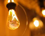 Une ampoule décorative aux filaments lumineux, projetant une lumière chaude et dorée. L'étiquette ampoule est subtilement intégrée dans le design.