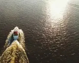 Bateau blanc naviguant sur l'eau sombre, laissant une traînée écumeuse. Le soleil brille, rappelant le temps de séchage Sikaflex.