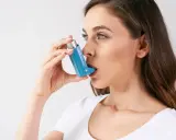 Frau mit Inhalator, der bei Asthma hilft. Hohe Luftfeuchtigkeit kann Symptome verschlimmern.