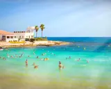 Sonnige Küste in Costa Calida, Spanien, mit vielen Menschen, die im türkisfarbenen Meer schwimmen.