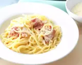 Une assiette de spaghetti crémeux, parsemée de lardons et de parmesan. La vraie recette carbonara italienne, un délice simple et authentique.