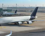 Samolot Airbus A380 na lotnisku, w tle inne samoloty i terminal. Cisza na płycie lotniska, jakby zapowiadała strajk linii lotniczych.