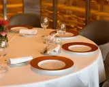Une table dressée avec soin, des assiettes élégantes et des verres à moitié pleins, le tout dans une ambiance feutrée. L'art de la table est à l'honneur.