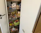 Ein offener Apothekerschrank mit vielen Lebensmitteln. Hier wird gezeigt, wie man einen Apothekerschrank organisieren kann, um Platz zu sparen.
