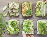 Sześć pysznych kanapek z awokado, ozdobionych warzywami, kiełkami i orzechami. Idealne na zdrowy lunch!