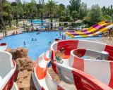 Disfruta de los mejores campings de Catalunya con piscinas y toboganes acuáticos. Familias se divierten en un día soleado.