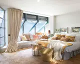 Habitación acogedora con cama grande, cojines coloridos y una zona de lectura junto a la ventana. Ideas para decorar habitacion con estilo natural.