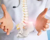 Lekarz prezentuje model kręgosłupa, sugerując proces diagnostyczny lub terapeutyczny, który może pomóc w uzyskaniu grupy inwalidzkiej na kręgosłup.