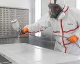 Profesional aplicando pintura blanca a una puerta con pistola pulverizadora. Aprende como lacar puertas en blanco para un acabado perfecto.