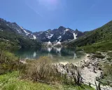 Widok na Morskie Oko z górami w tle i turystami na brzegu.