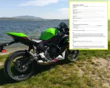 Zielony motocykl Kawasaki przy jeziorze, obok dokument "Umowa kupna-sprzedaży motocykla".