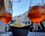 Dwa drinki Aperol Spritz i miseczka chipsów na stoliku. Czy alkohol podnosi cholesterol? To pytanie zadaje sobie wielu, delektując się takimi przekąskami.