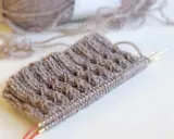 Knitted swatch with textured pattern and yarn on needles.