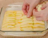 Ręce układają plasterki jabłek na cieście. Powstaje pyszne ciasto z jabłkami, gotowe do pieczenia.