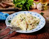 Ein Teller mit Krautsalat, garniert mit Petersilie. Daneben liegen Gabel und Löffel. Ein leckeres Krautsalat Rezept für dich!