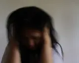 Mujer con cabello oscuro, con las manos en la cabeza, rostro agachado. Expresión de angustia, quizás por la ansiedad antes de la regla.