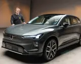 Ein Mann steht neben einem modernen, grauen Volvo EX90.