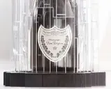 Dom Pérignon Vintage 2012 in einer modernen, transparenten Hülle mit dunklem Holzsockel.