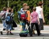 Niños con mochilas y un carrito cruzan la calle, marcando el regreso a la rutina de septiembre.
