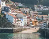 Casas de colores se aferran a la ladera en uno de los pueblos con encanto en Asturias, con el mar turquesa al frente.