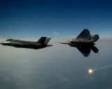 Zwei Tarnkappen-Kampfflugzeuge, ein F-35 und ein F-22, fliegen im Tandem über den Wolken. Ein F-22 schießt eine Leuchtrakete ab.
