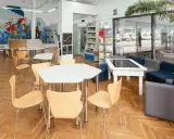 Spazi della scuola luminosi con scaffali, tavoli, sedie e un murale colorato. Un'area accogliente per imparare e giocare.