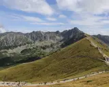 Kamienisty szlak na Kasprowy Wierch, pełen turystów, wije się po zielonych zboczach Tatr.